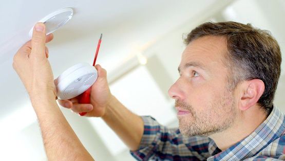 An electrician installing a smoke alarm